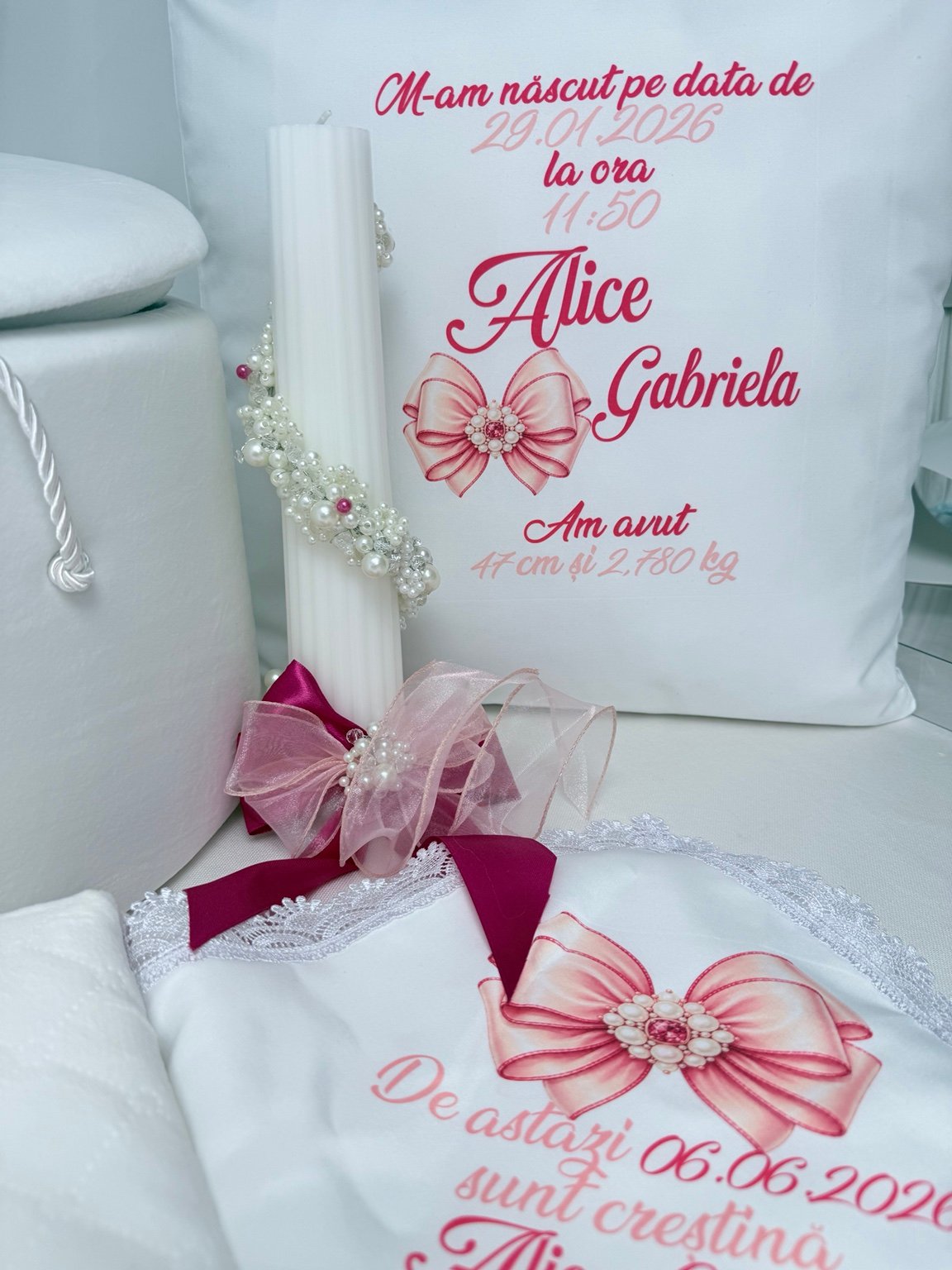 Lumânare albă cu perle în spirală și fundă roz și fucsia, alături de pernă personalizată