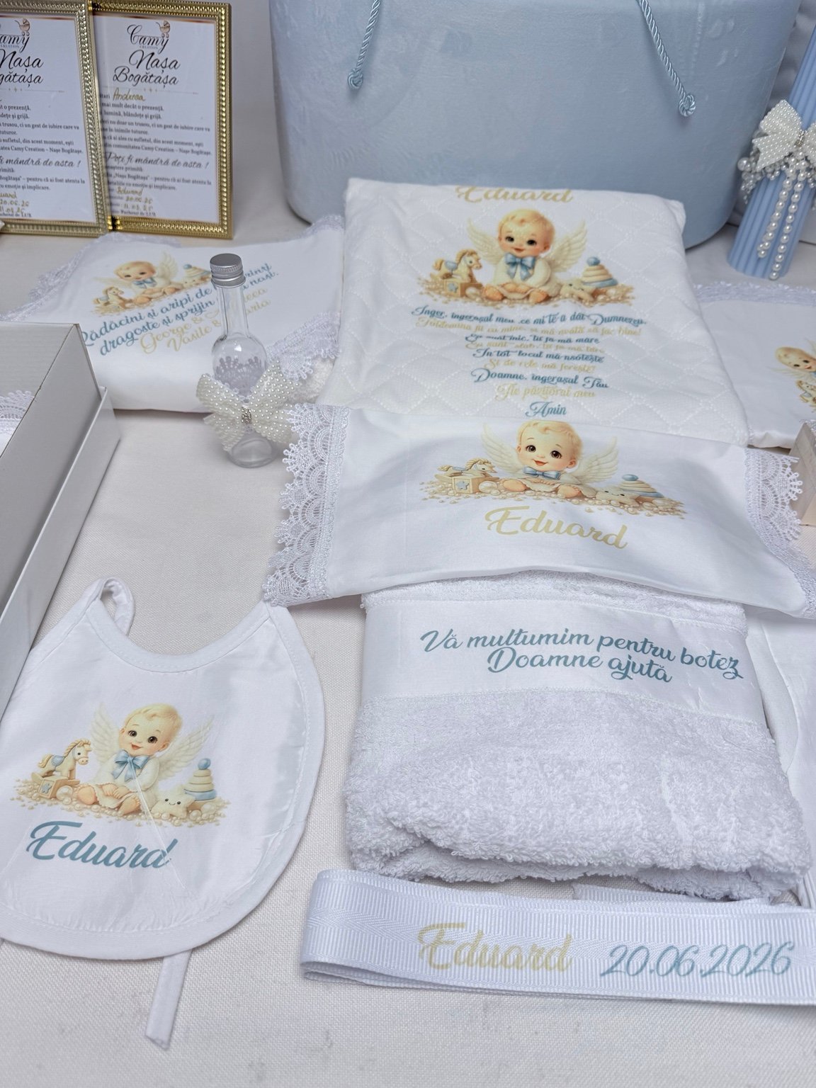 Textile de botez cu îngeraș ilustrat, băvețică și fașă personalizate, alături de sticluța cu fundă