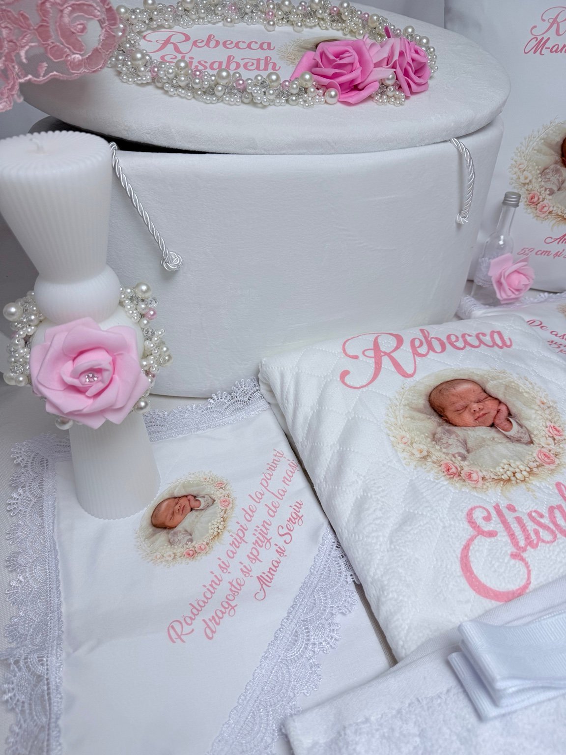 Lumânare albă clepsidră cu trandafir roz și perle, lângă cufăr și textile personalizate pentru botez
