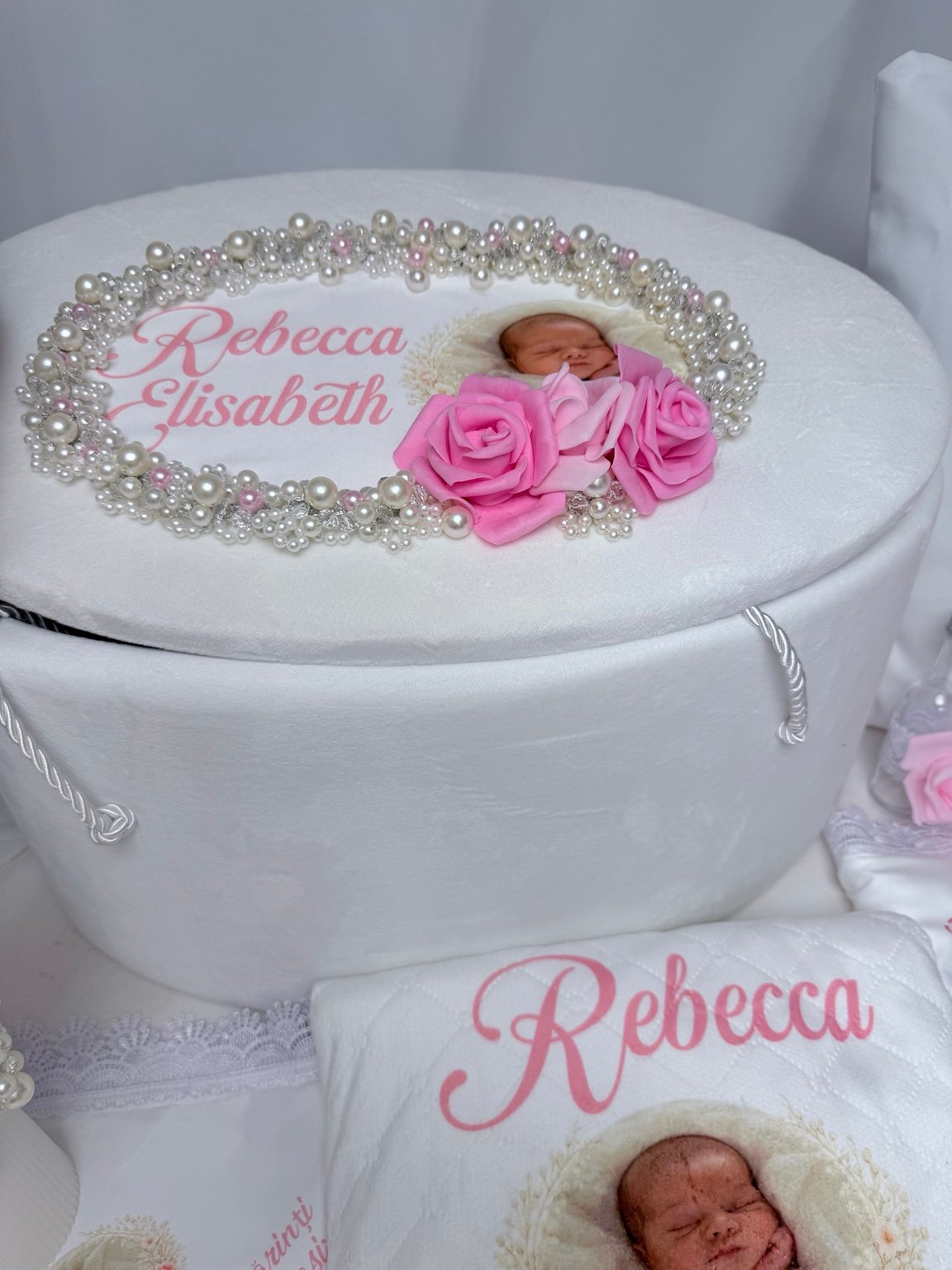 Detaliu al capacului de cufăr cu nume, fotografie, contur oval din perle decorative și trei trandafiri roz
