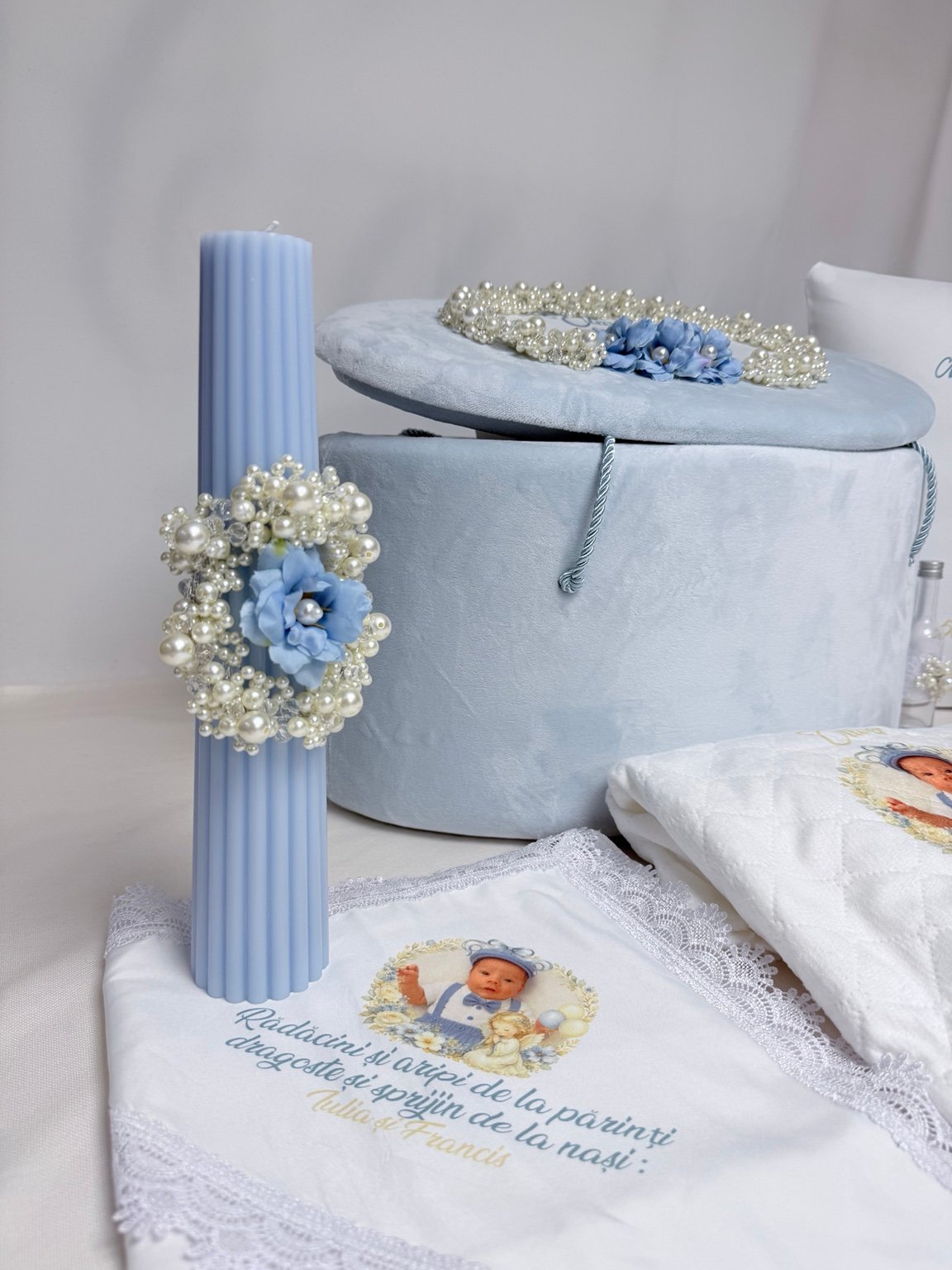 Lumânare bleu canelată cu floare albastră și ornament oval din perle decorative, lângă cufărul asortat