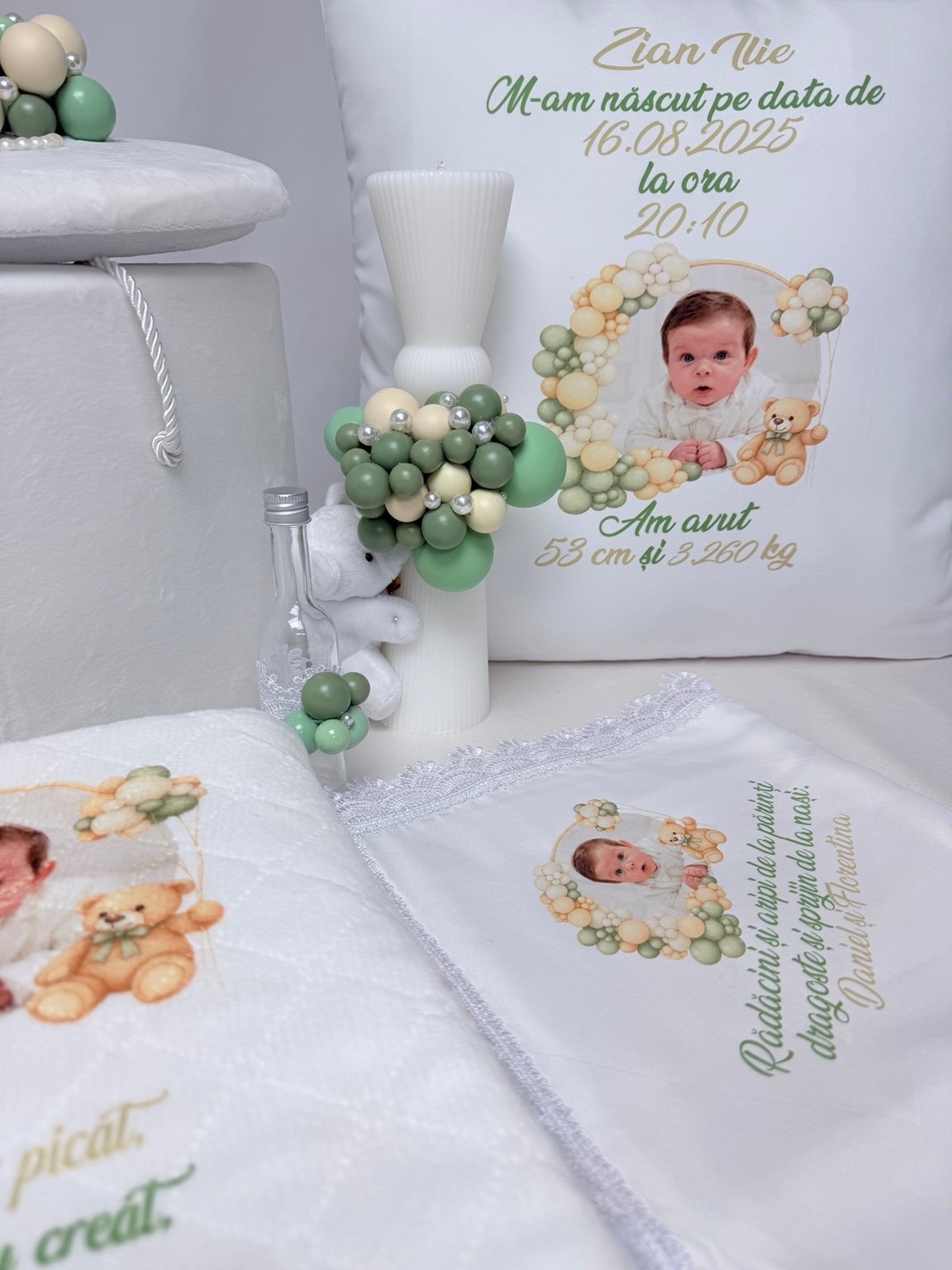 Pernă personalizată cu fotografia bebelușului și datele nașterii, lângă lumânare albă cu decor verde