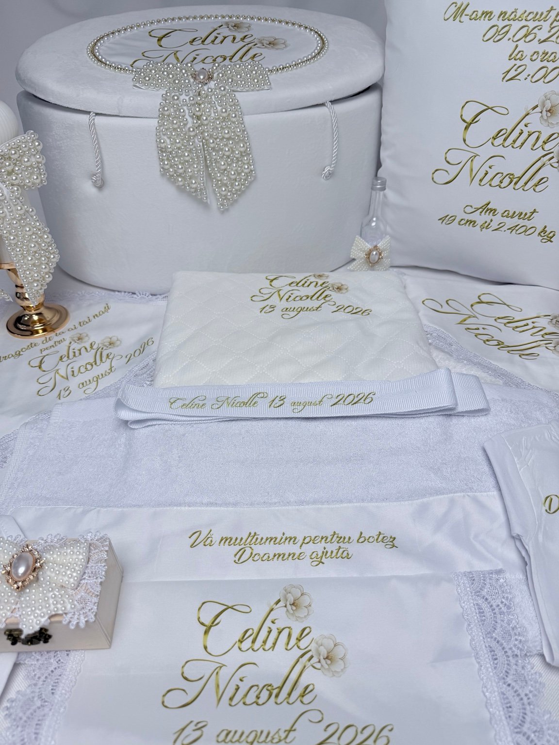 Textile albe de botez personalizate cu nume, dată și flori crem, alături de cufăr, pernă și accesorii