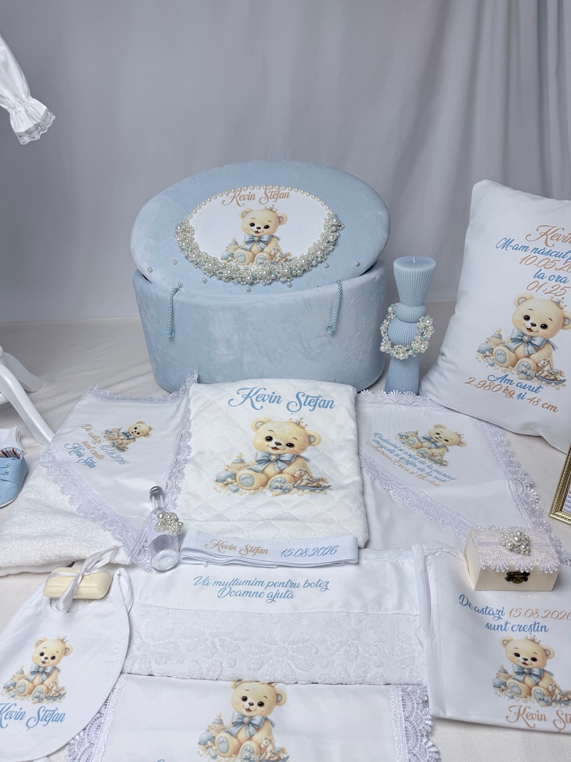 Textile albe personalizate cu ursuleț, nume și dată, alături de cufărul bleu și accesoriile cu perle
