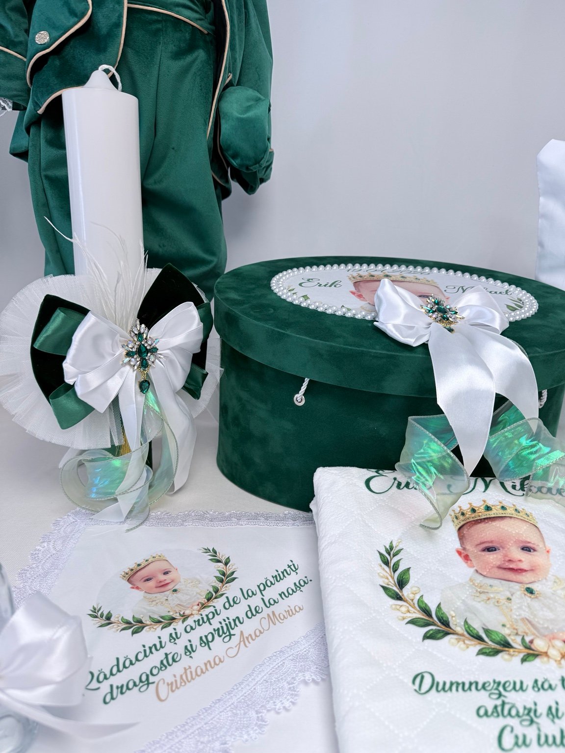 Lumânare albă dreaptă cu fundă albă peste decor verde și broșă cu pandantiv, lângă cufărul Smarald Imperial