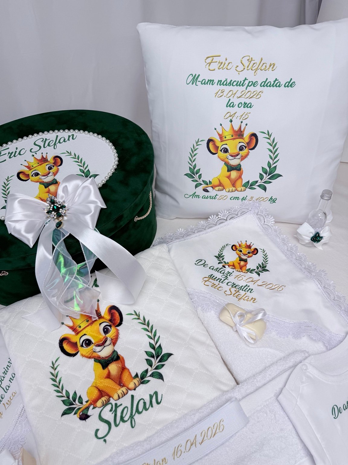 Pernă cu datele nașterii și leuț ilustrat, lângă cufărul verde, pătură și sticluța decorată