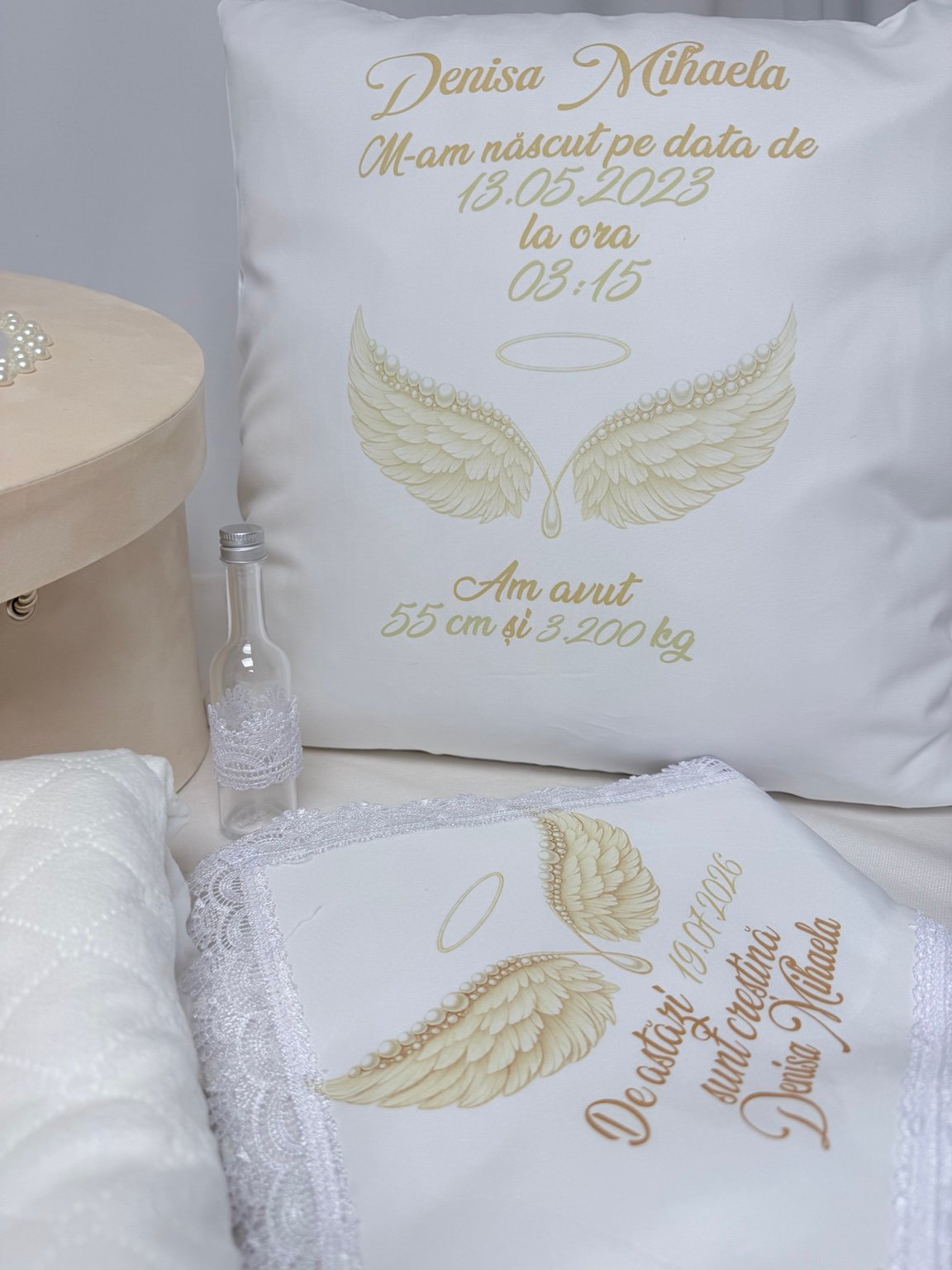 Pernă personalizată cu datele de la naștere și aripi ilustrate, alături de sticluța pentru mir și textile cu dantelă