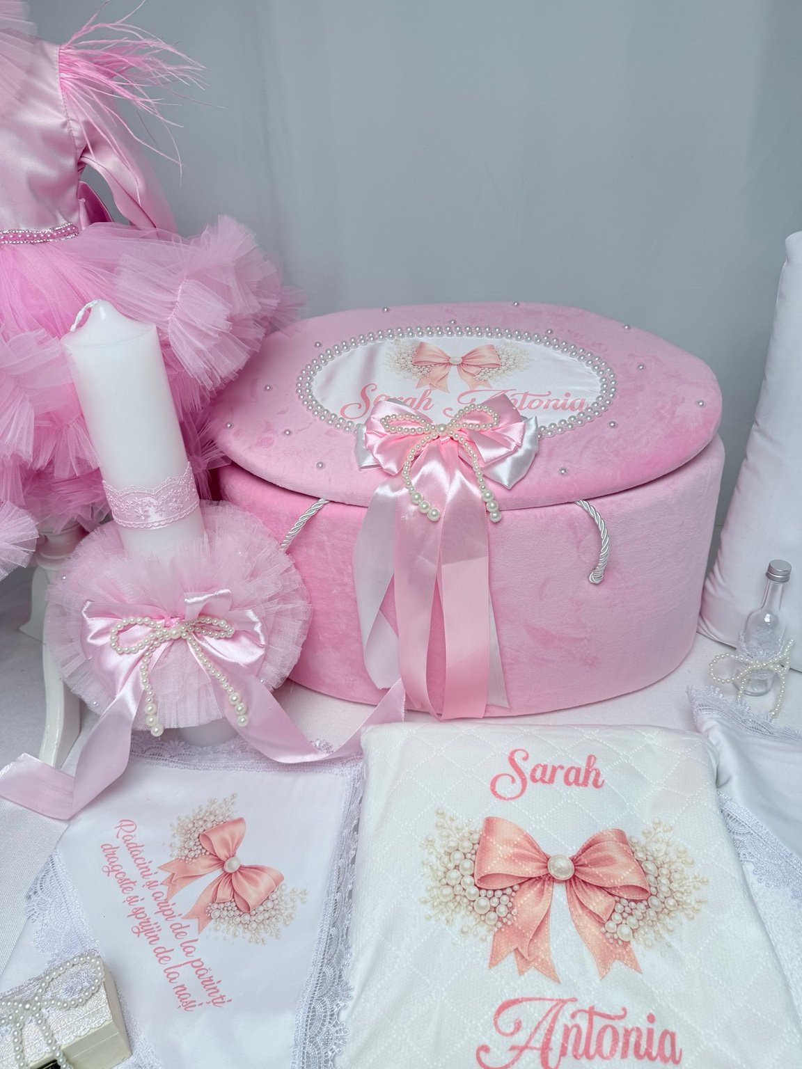 Detaliu al lumânării albe cu dantelă roz, rozetă voluminoasă și fundă conturată cu perle decorative