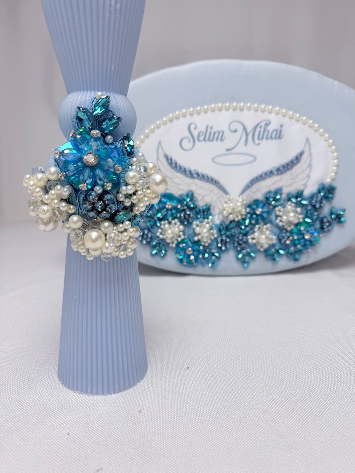 Detaliu al lumânării bleu canelate, cu floare turcoaz fațetată și grupuri de perle decorative