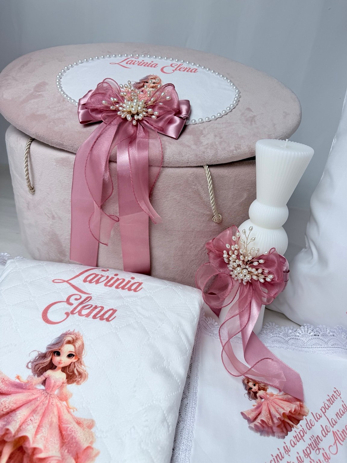 Detaliu al fundelor roz și broșelor ramificate cu perle decorative de pe cufăr și lumânarea albă