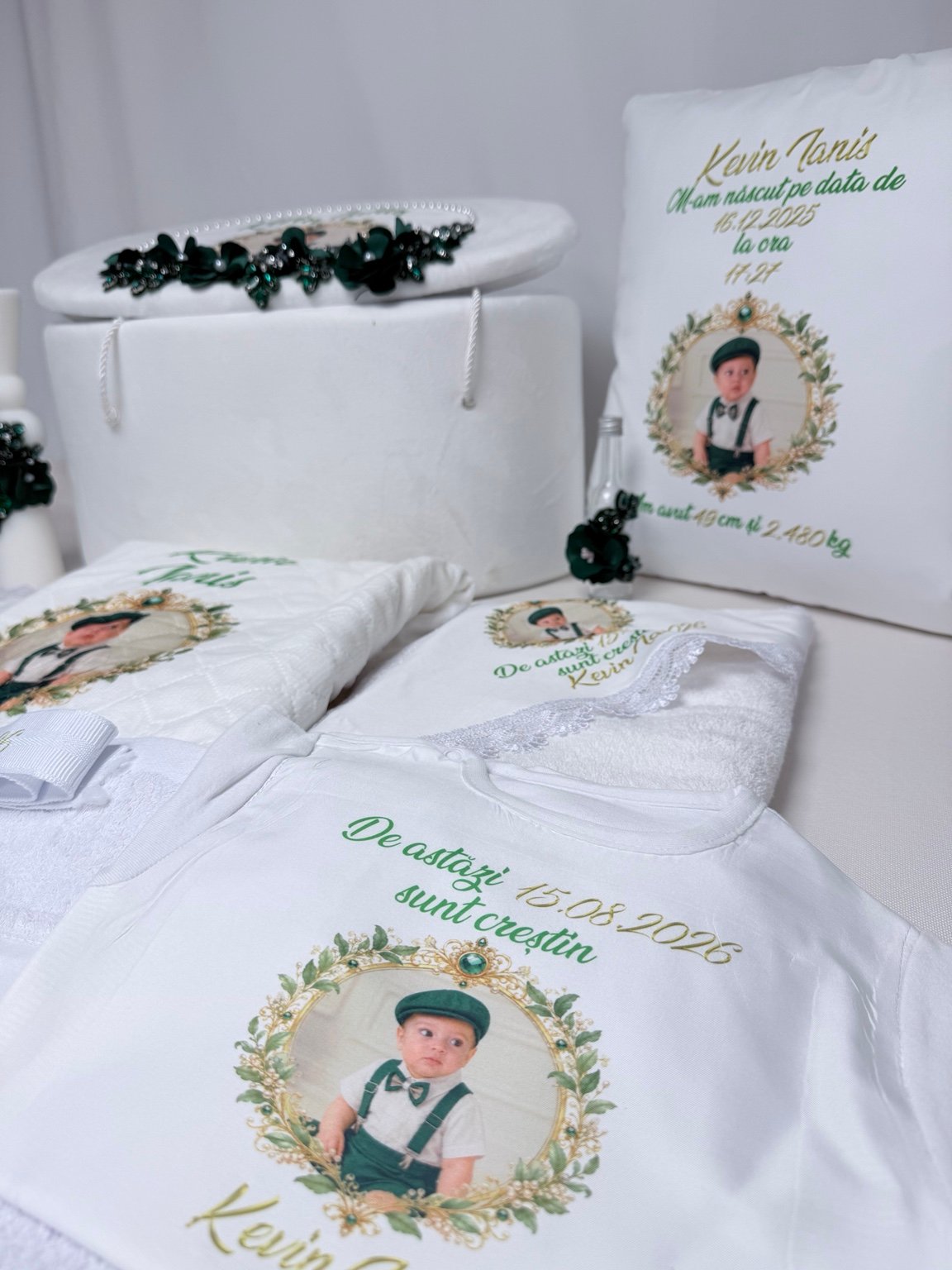 Body alb personalizat cu portret în ramă aurie și verde, alături de cufăr, pernă și textile pentru botez